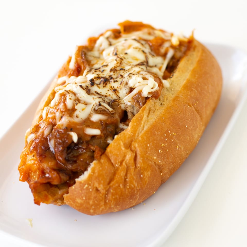 A GoPho Vietnamese sandwich with melted cheese and savory filling on a white plate.
