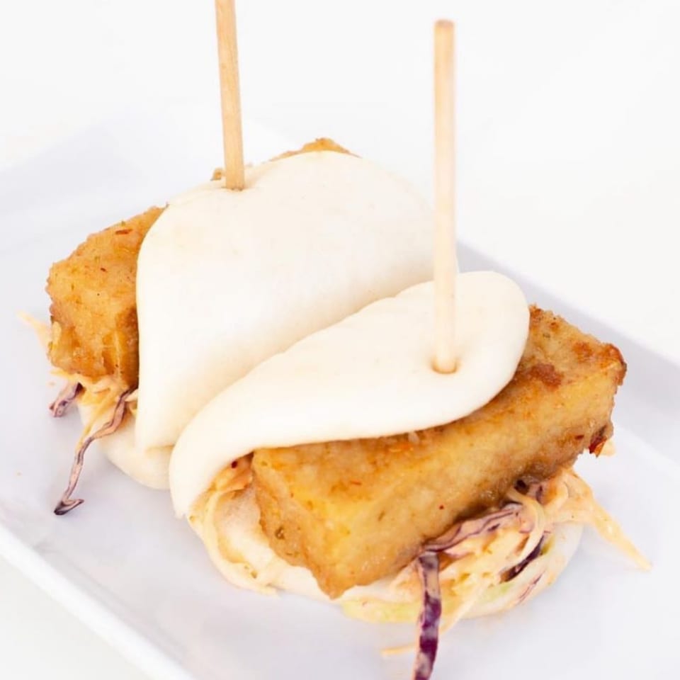 Two GoPho crispy tofu bao buns with slaw and wooden skewers on a white plate.